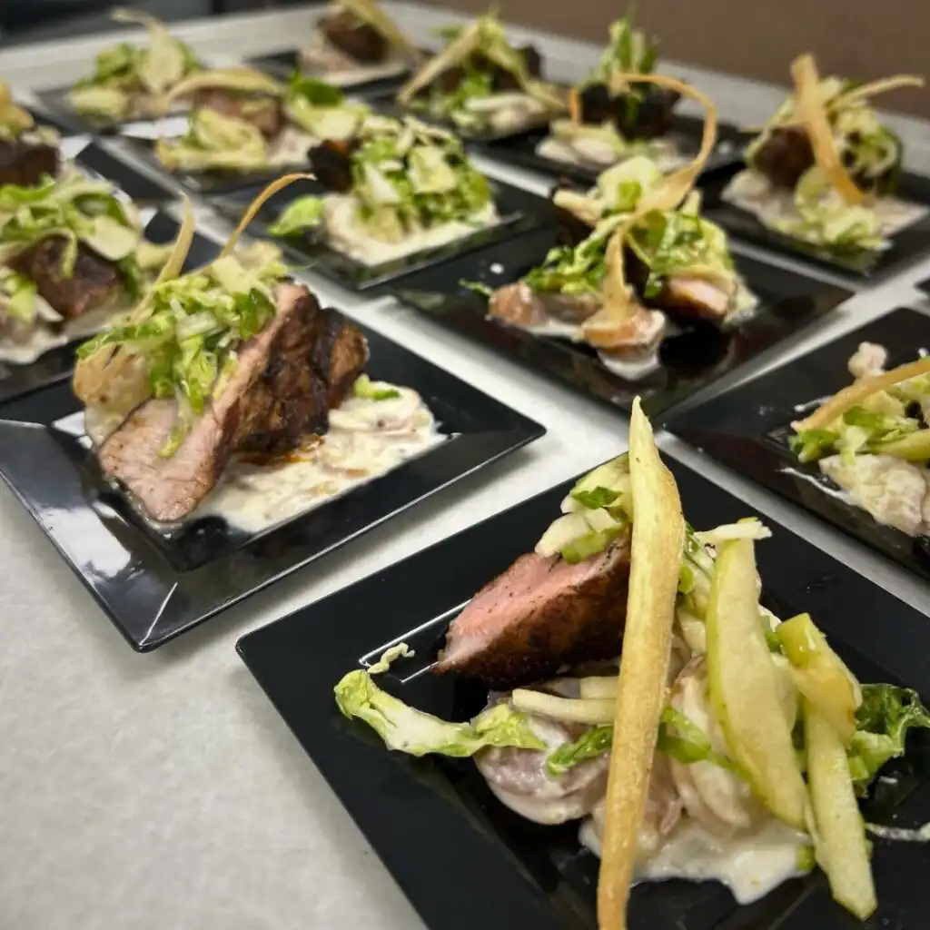 Slices of seared pork tenderloin on creamy mushroom sauce, garnished with crisp greens and fried veggie strips