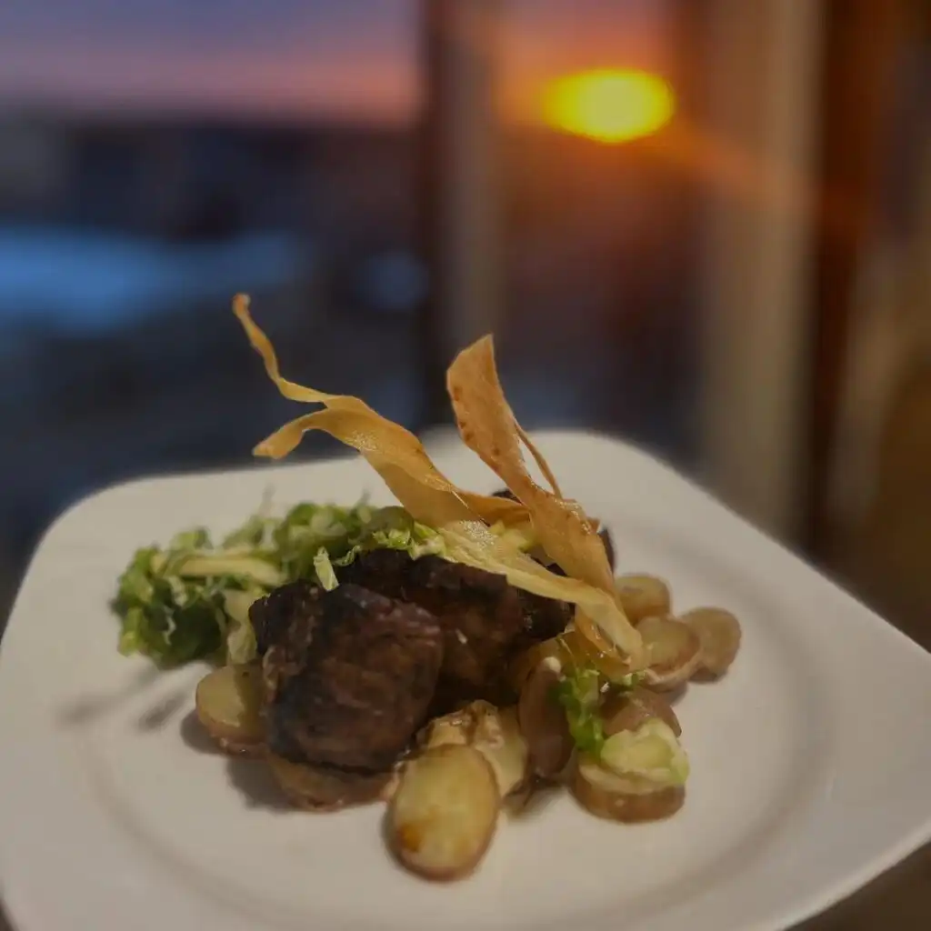 Seared pork medallions with baby potatoes, mushrooms, greens, and crispy tortilla strips on a plate